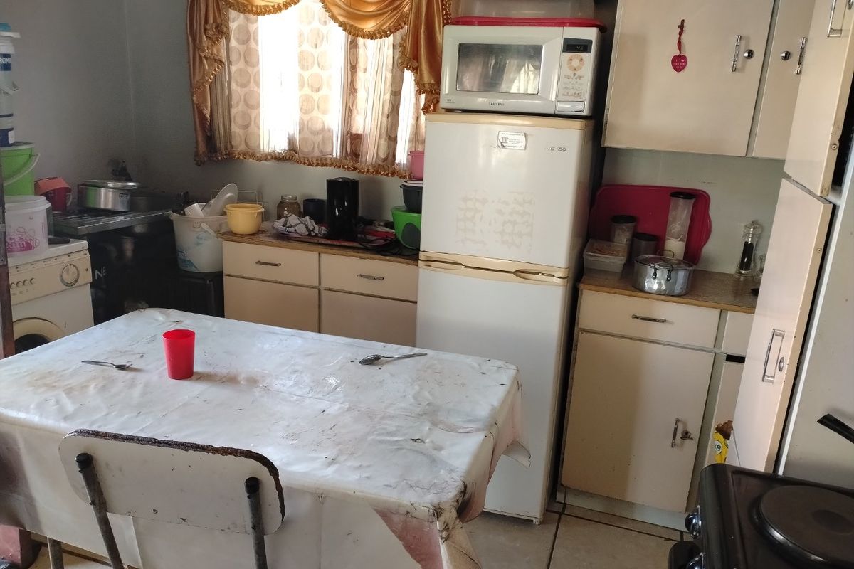 A dated kitchen featuring original cabinetry, laminate countertops, and tiled flooring, offering significant potential for modernization and renovation.