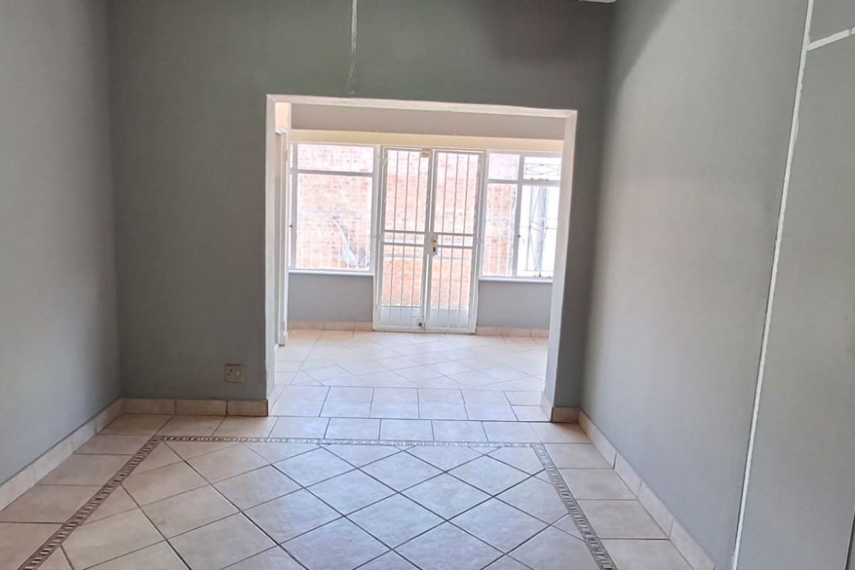 An empty bedroom featuring tiled flooring, built-in cupboards, and a secure access point leading to an enclosed patio area.