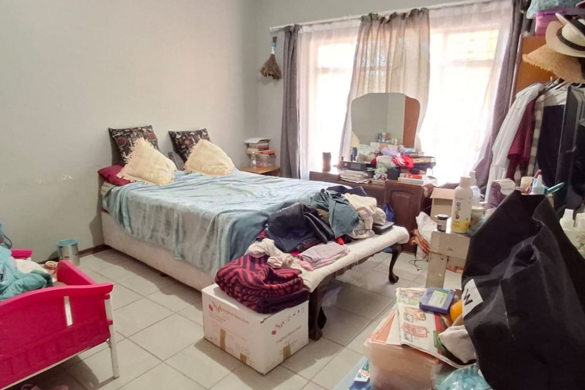 A bedroom featuring tiled flooring and large windows with curtain rails, offering a functional space ready for personalization.