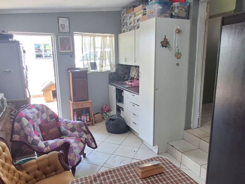 A compact kitchen area featuring built-in cabinetry, tiled flooring, and a tiled backsplash, providing functional storage and preparation space.