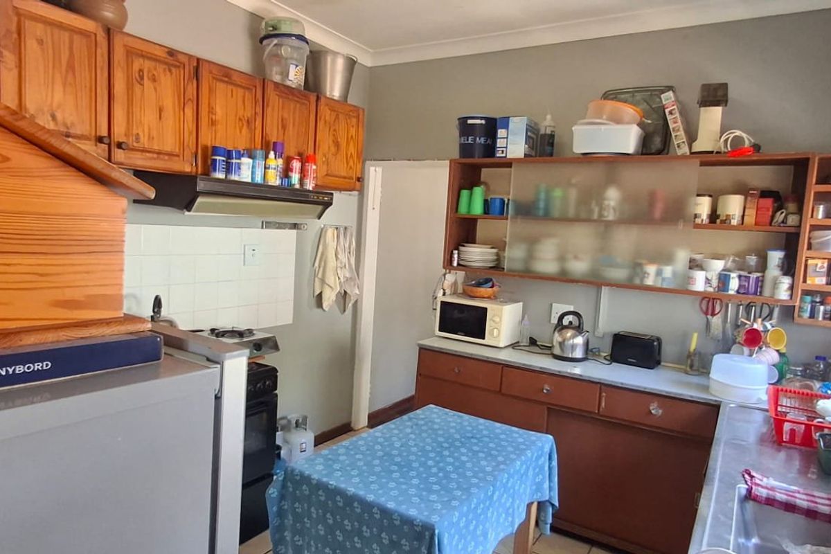 A functional kitchen featuring wooden cabinetry, a built-in stove with extractor fan, and a stainless steel sink with tiled backsplash.