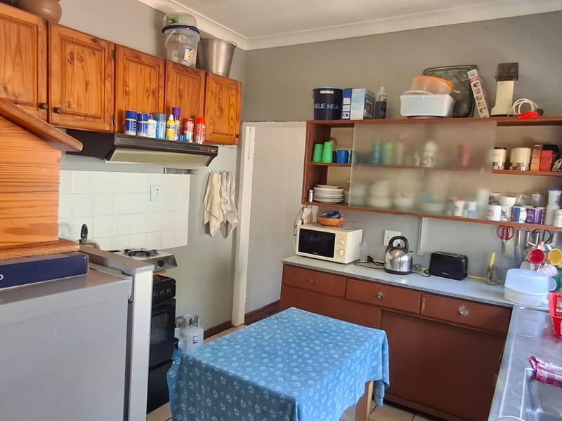 A functional kitchen featuring wooden cabinetry, a built-in stove with extractor fan, and a stainless steel sink with tiled backsplash.