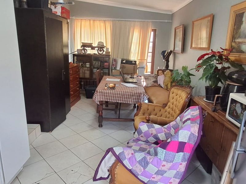 Open plan living and kitchen area featuring tiled flooring and built-in cabinetry, offering a functional layout with potential for modernization.