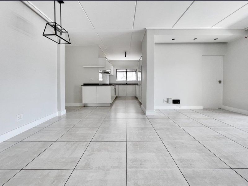 Spacious open-plan living area featuring neutral tiled flooring, modern kitchen cabinetry, and clean finishes, providing a versatile blank canvas for your interior design.