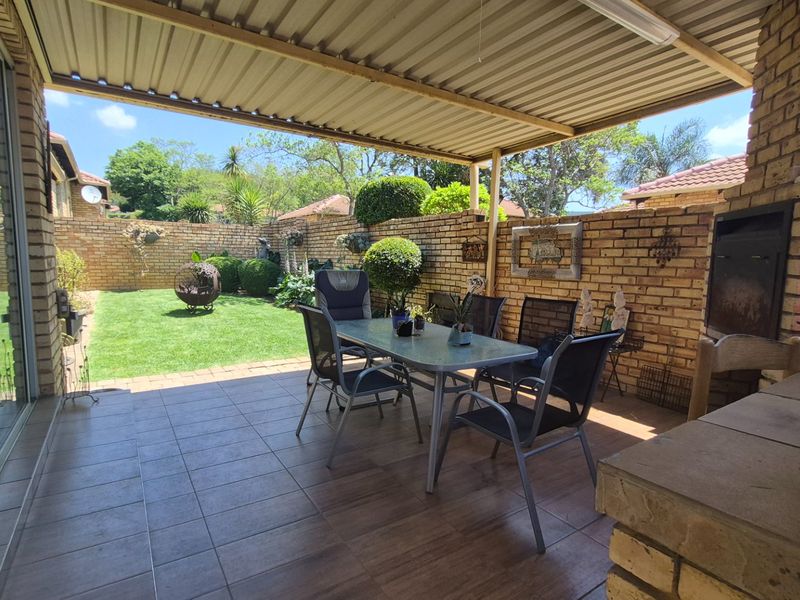 Covered patio area featuring tiled flooring, a built-in braai, and direct access to a private rear garden.