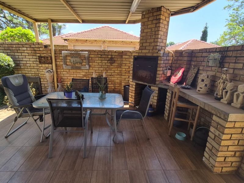 A covered outdoor patio featuring a built-in brick braai, tiled flooring, and enclosed by brick boundary walls, ideal for outdoor entertaining.