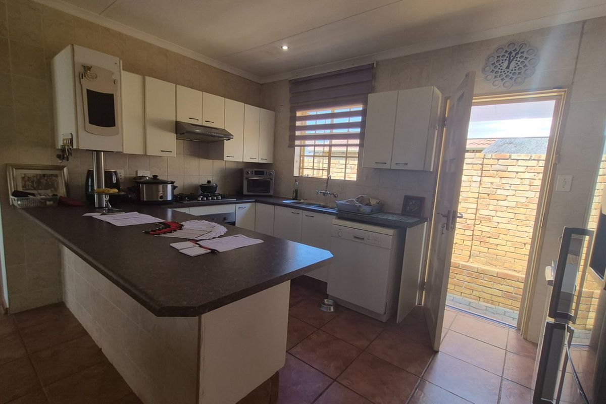 Functional kitchen featuring built-in cabinetry, a breakfast bar, gas hob, and direct access to the rear exterior area.