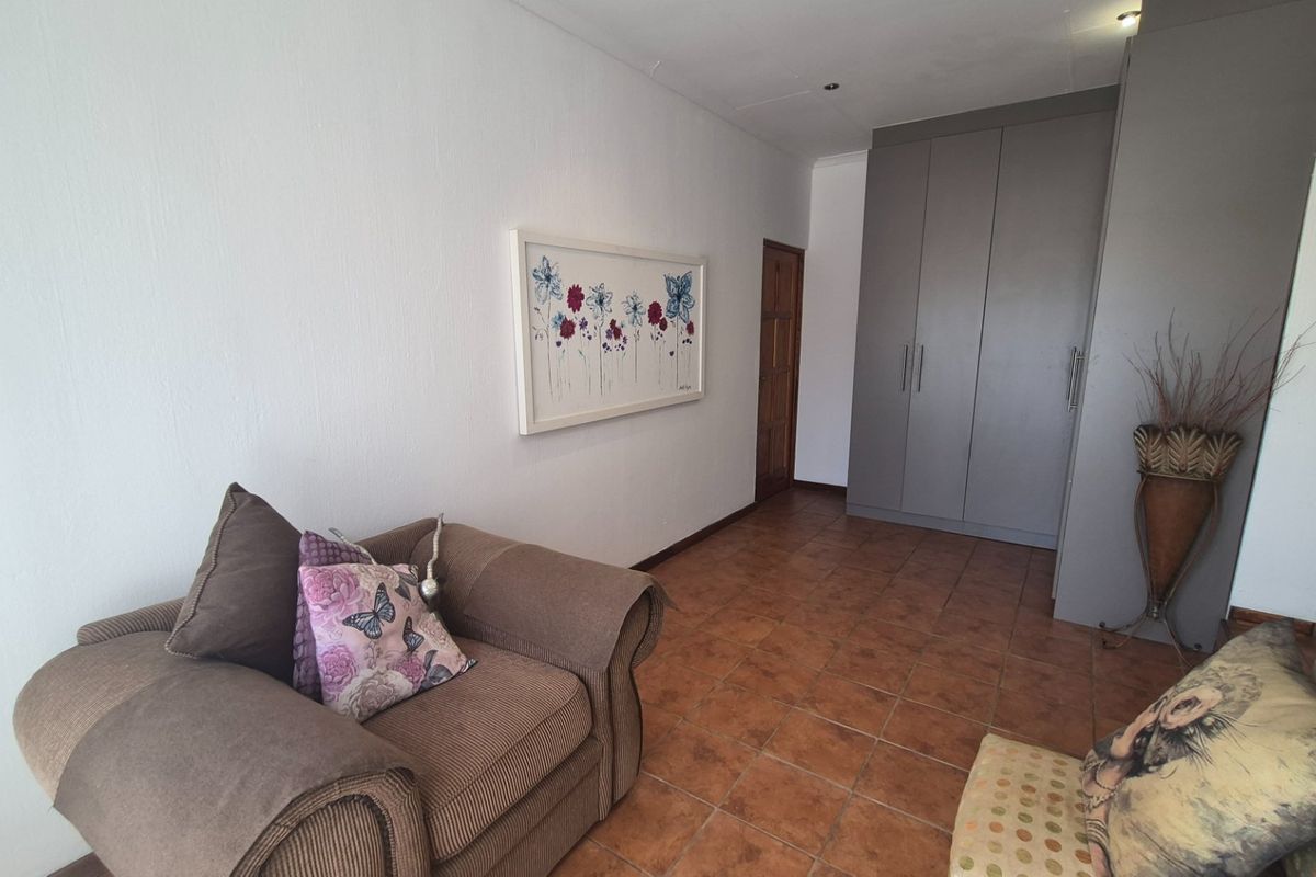 A bedroom featuring tiled flooring, recessed downlights, and grey built-in cupboards providing ample storage space.