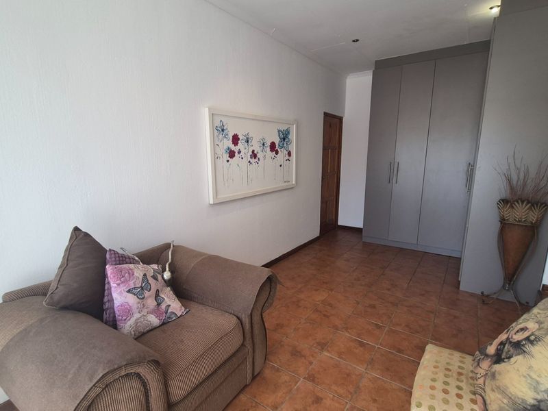 A bedroom featuring tiled flooring, recessed downlights, and grey built-in cupboards providing ample storage space.