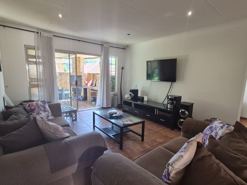 A comfortable living room featuring tiled flooring, recessed lighting, and a sliding glass door providing direct access to the outdoor patio area.