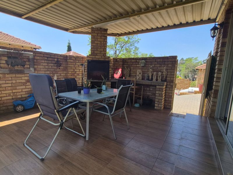 Covered outdoor patio featuring brick walls, tiled flooring, and a built-in braai, providing a functional space for outdoor entertaining.