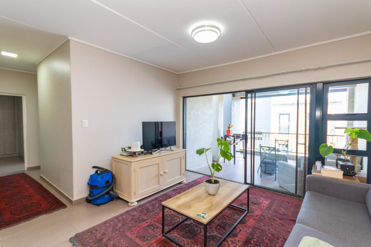 A living room featuring tiled flooring and large sliding glass doors that provide access to an outdoor balcony area.