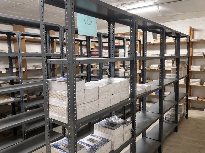 A functional utility storage area featuring industrial-grade metal shelving units and concrete flooring, suitable for organized commercial inventory or material storage.