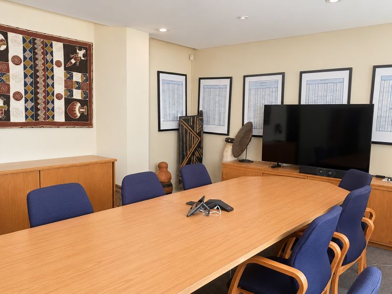 A professional office meeting room featuring built-in wooden cabinetry and recessed ceiling lighting, suitable for corporate discussions and presentations.