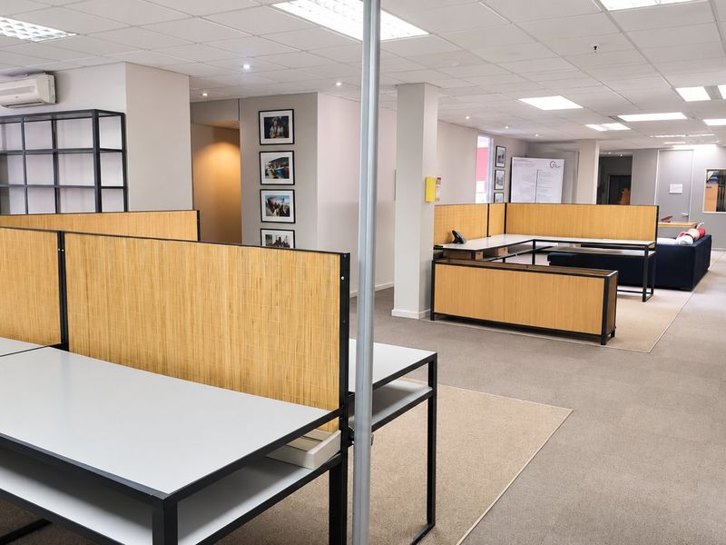 Open-plan commercial office space featuring modular workstations, suspended ceilings, recessed lighting, and neutral carpeted flooring throughout.