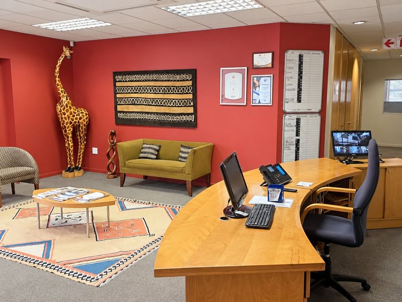 A professional commercial office space featuring a reception desk, waiting area, carpeted flooring, and recessed ceiling lighting.