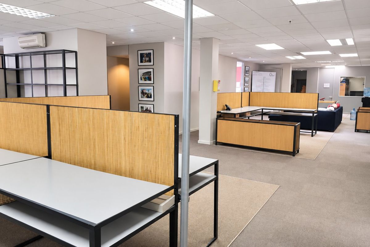 Open-plan commercial office space featuring modular workstations, suspended ceilings, recessed lighting, and neutral carpeted flooring throughout.