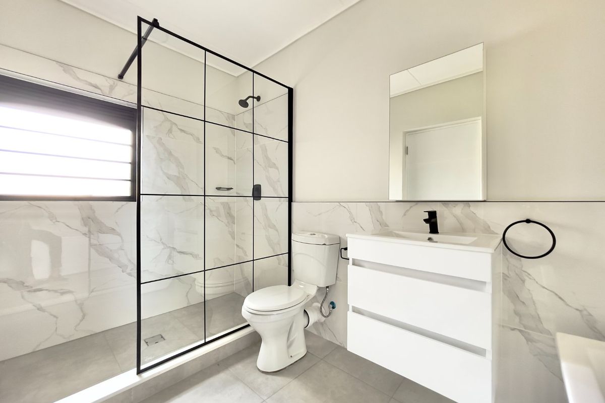 Modern bathroom featuring a walk-in shower with black-framed glass, a sleek wall-mounted vanity, and contemporary marble-look wall tiling.