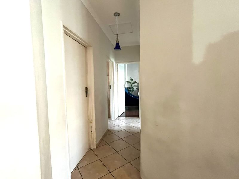 A functional hallway featuring tiled flooring and access to multiple rooms, currently requiring cosmetic attention to the walls and door frames.