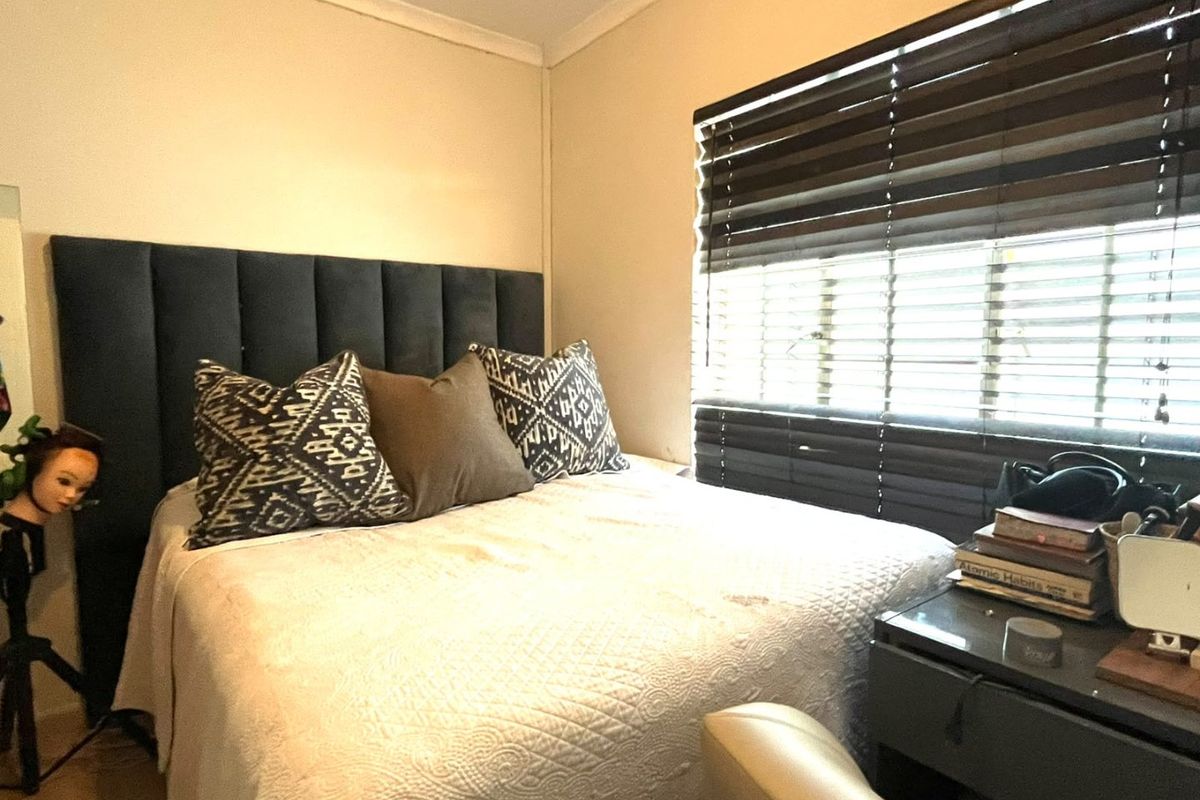 A cozy bedroom featuring a window with dark venetian blinds and decorative coving, providing a functional and comfortable sleeping space.
