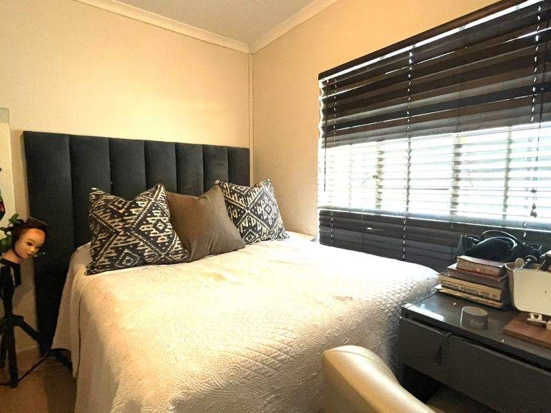 A cozy bedroom featuring a window with dark venetian blinds and decorative coving, providing a functional and comfortable sleeping space.