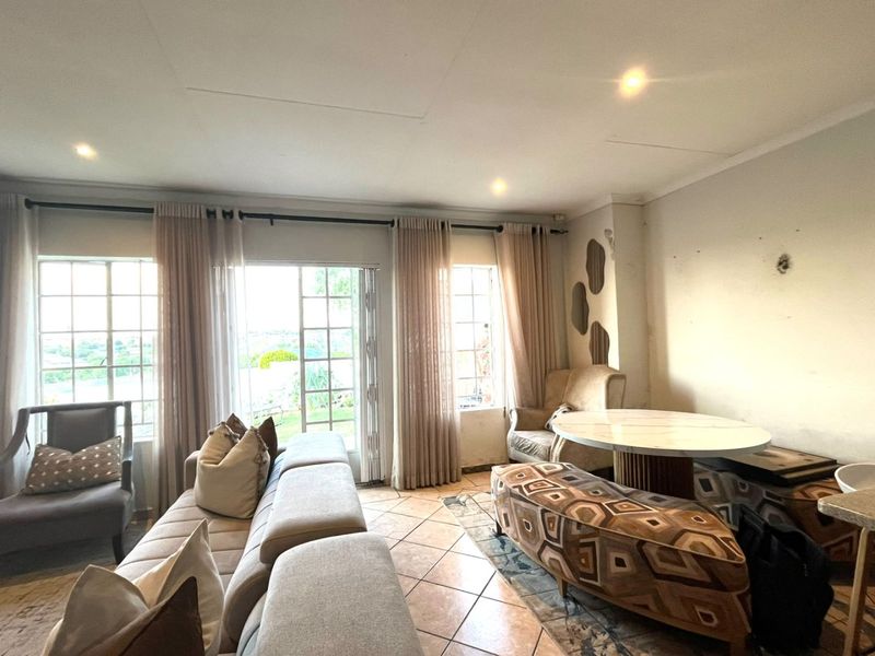 A living room featuring tiled flooring, recessed lighting, and access to the outdoors via french doors, currently requiring cosmetic wall repairs.