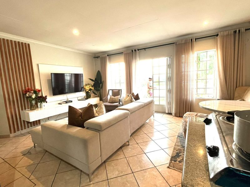 Spacious open-plan living area featuring tiled floors, modern vertical timber wall accents, and direct access to the outdoors through classic french doors.