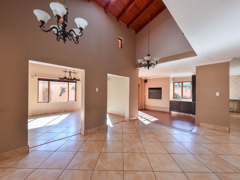 Spacious open-plan living area featuring high vaulted timber ceilings, tiled flooring, and a built-in fireplace, offering a versatile layout for modern living.