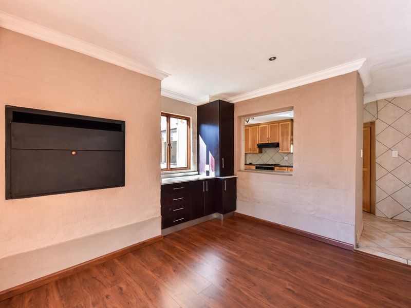 Open plan living area featuring laminate flooring, a built-in fireplace, and a convenient pass-through window connecting to the kitchen.