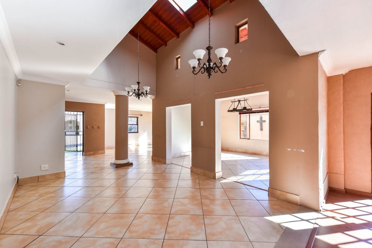 Spacious open-plan living area featuring high vaulted timber ceilings, skylights, and ceramic tiled flooring, offering a bright and airy atmosphere.