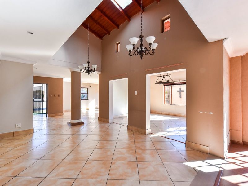 Spacious open-plan living area featuring high vaulted timber ceilings, skylights, and ceramic tiled flooring, offering a bright and airy atmosphere.