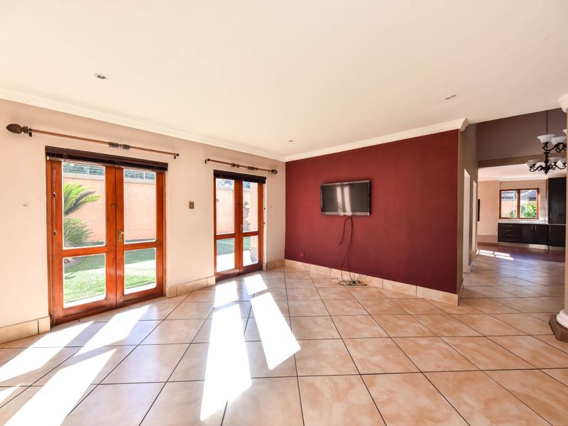 Spacious living area featuring tiled flooring, recessed lighting, and double doors providing direct access to the garden.