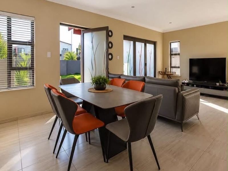 Spacious open-plan living and dining area featuring neutral tiled flooring, modern aluminium window frames, and large sliding doors providing access to the outdoor space.