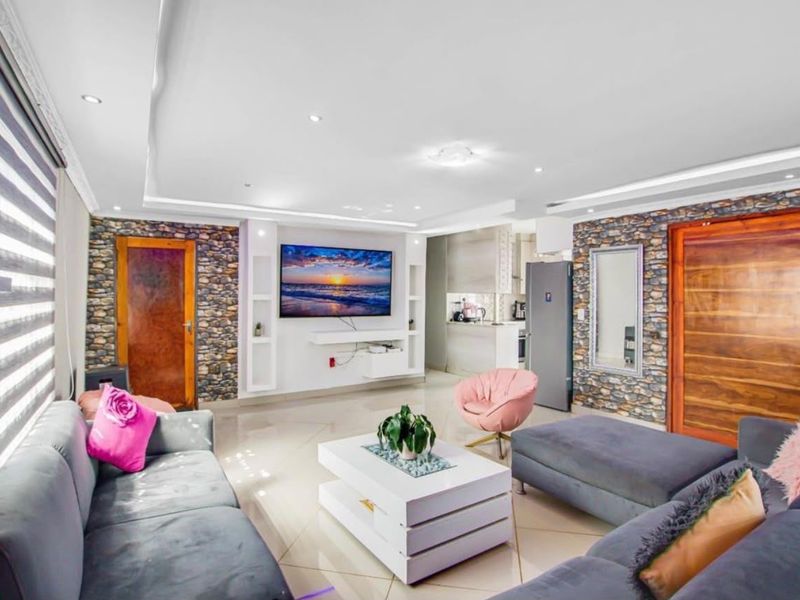 Spacious open-plan living area featuring stone veneer accent walls, recessed ceiling lighting, and modern tiled flooring, seamlessly connecting to the kitchen space.