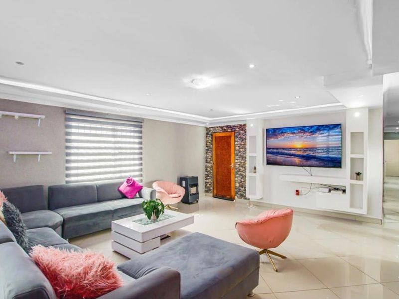Spacious living room featuring tiled flooring, recessed ceiling lighting, a stone accent wall, and custom built-in shelving units.