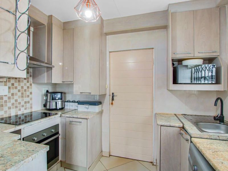 A functional kitchen featuring light wood cabinetry, granite countertops, a built-in oven with hob, and a tiled backsplash.
