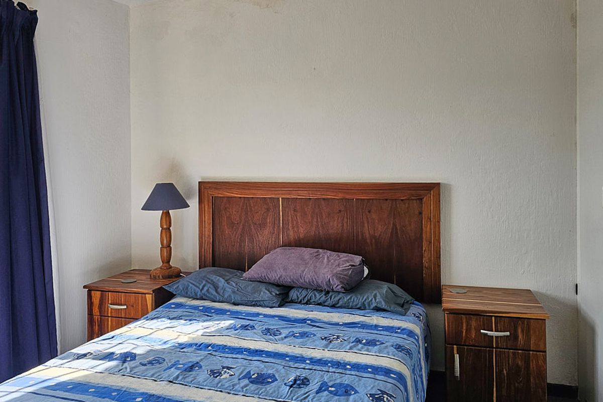A functional bedroom featuring a built-in wardrobe and natural light from the side window.