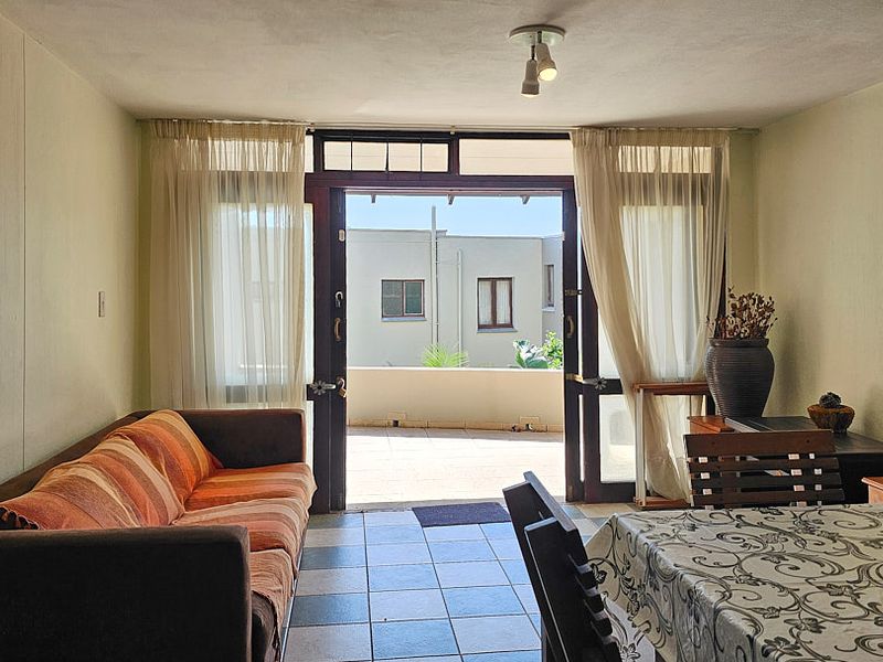 Open plan living and dining area featuring tiled flooring and direct access to an outdoor balcony through double glass doors.