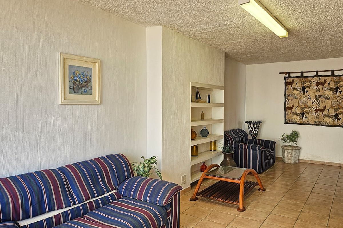 A living room featuring tiled flooring, textured ceilings, and built-in shelving units.