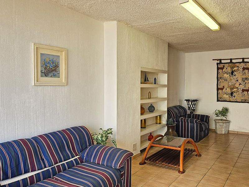 A living room featuring tiled flooring, textured ceilings, and built-in shelving units.