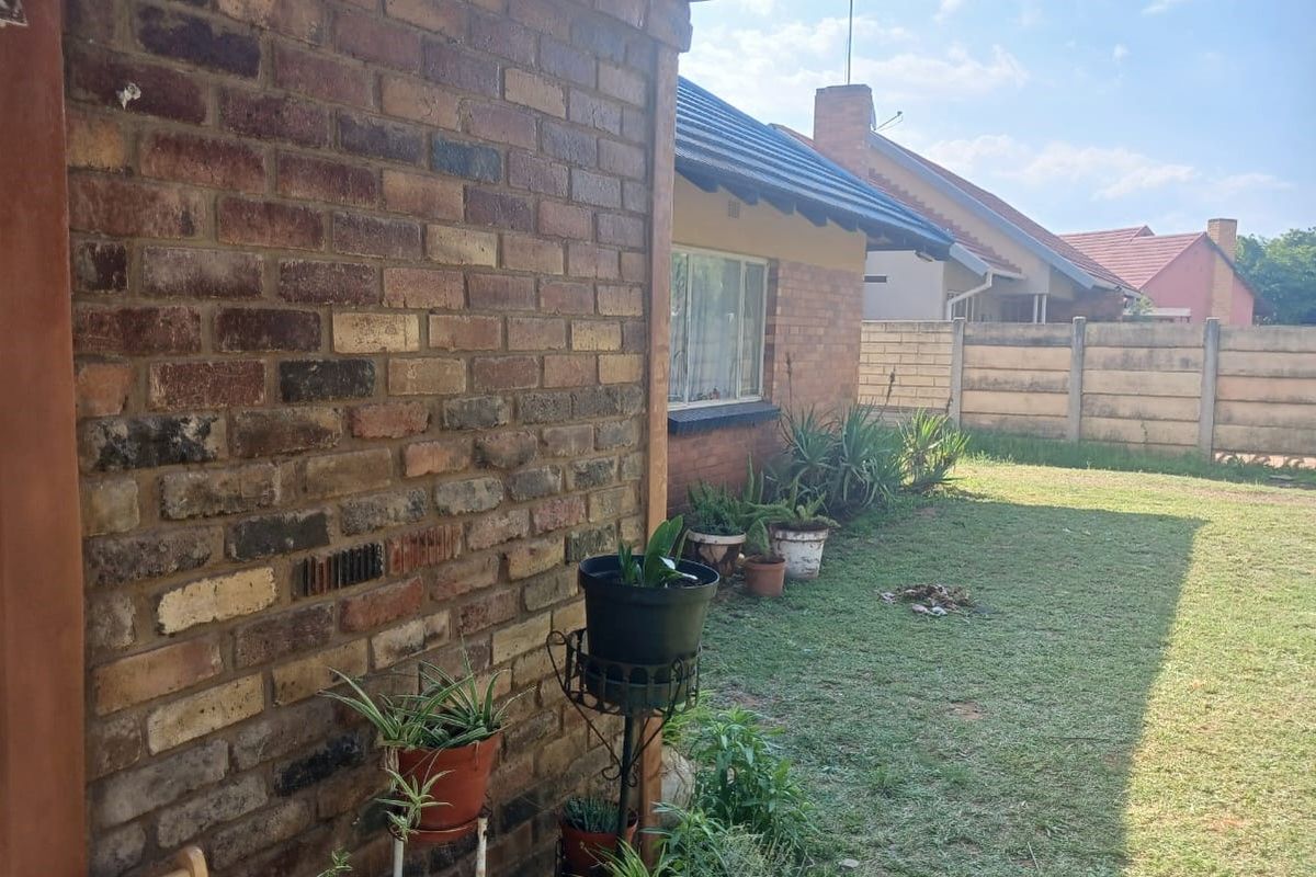A view of the rear exterior of the house featuring face brick walls, a tiled roof, and a private garden with a precast boundary wall.
