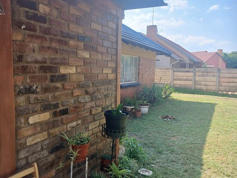 A view of the rear exterior of the house featuring face brick walls, a tiled roof, and a private garden with a precast boundary wall.