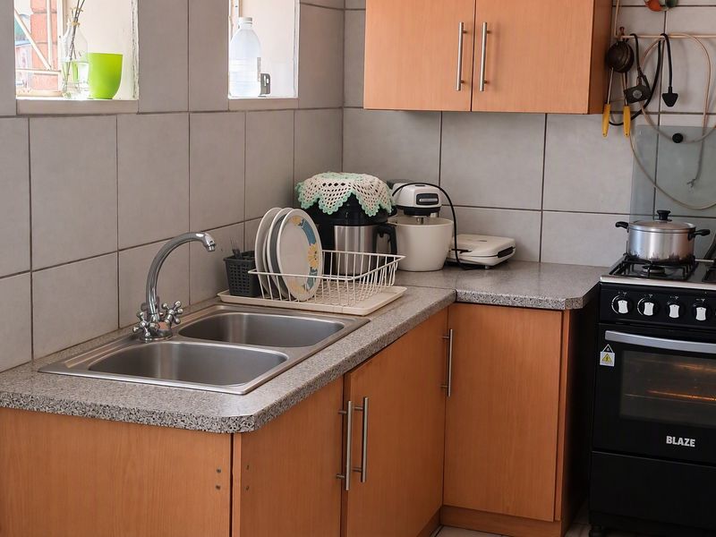 A functional kitchen featuring wooden cabinetry, laminate countertops, a double bowl stainless steel sink, and a freestanding gas stove.