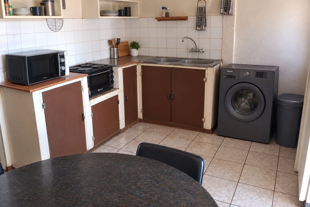 A functional kitchen area featuring tiled flooring, a double sink, and built-in cabinetry with a tiled backsplash.