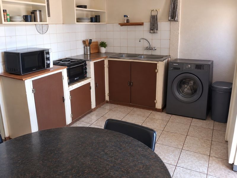 A functional kitchen area featuring tiled flooring, a double sink, and built-in cabinetry with a tiled backsplash.