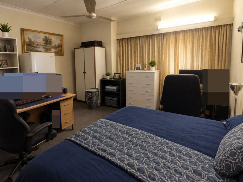 A functional bedroom featuring a ceiling fan, neutral wall finishes, and floor-to-ceiling curtains, providing a comfortable and versatile living space.