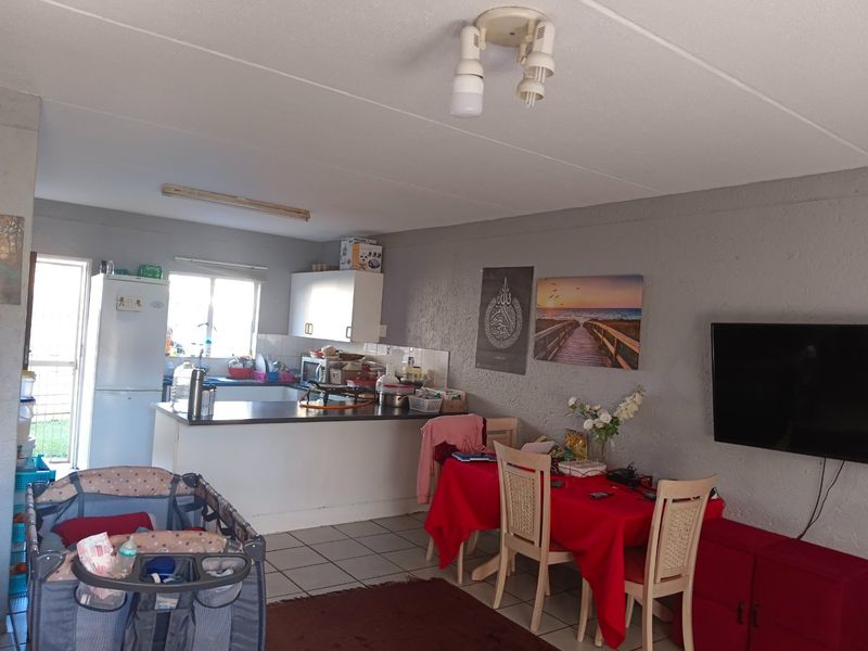 Open plan living and dining area featuring a functional kitchen with built-in cabinetry and tiled flooring throughout.