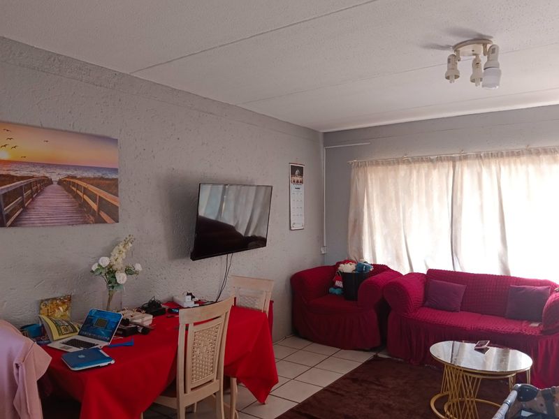 A living room area featuring tiled flooring, textured walls, and a ceiling-mounted light fixture, providing a functional space for relaxation.