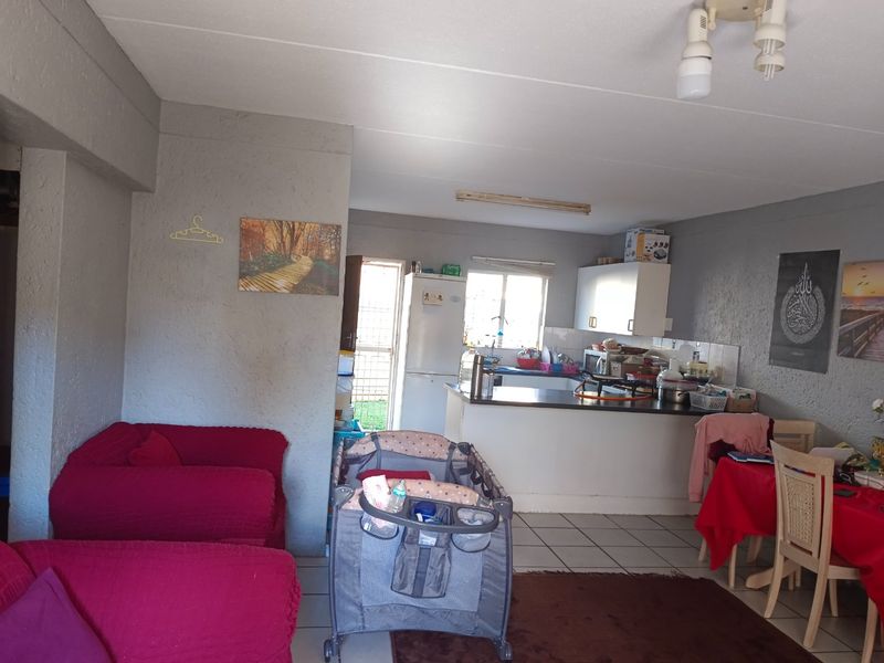 Open plan living and kitchen area featuring tiled flooring, functional cabinetry, and direct access to an exterior door.