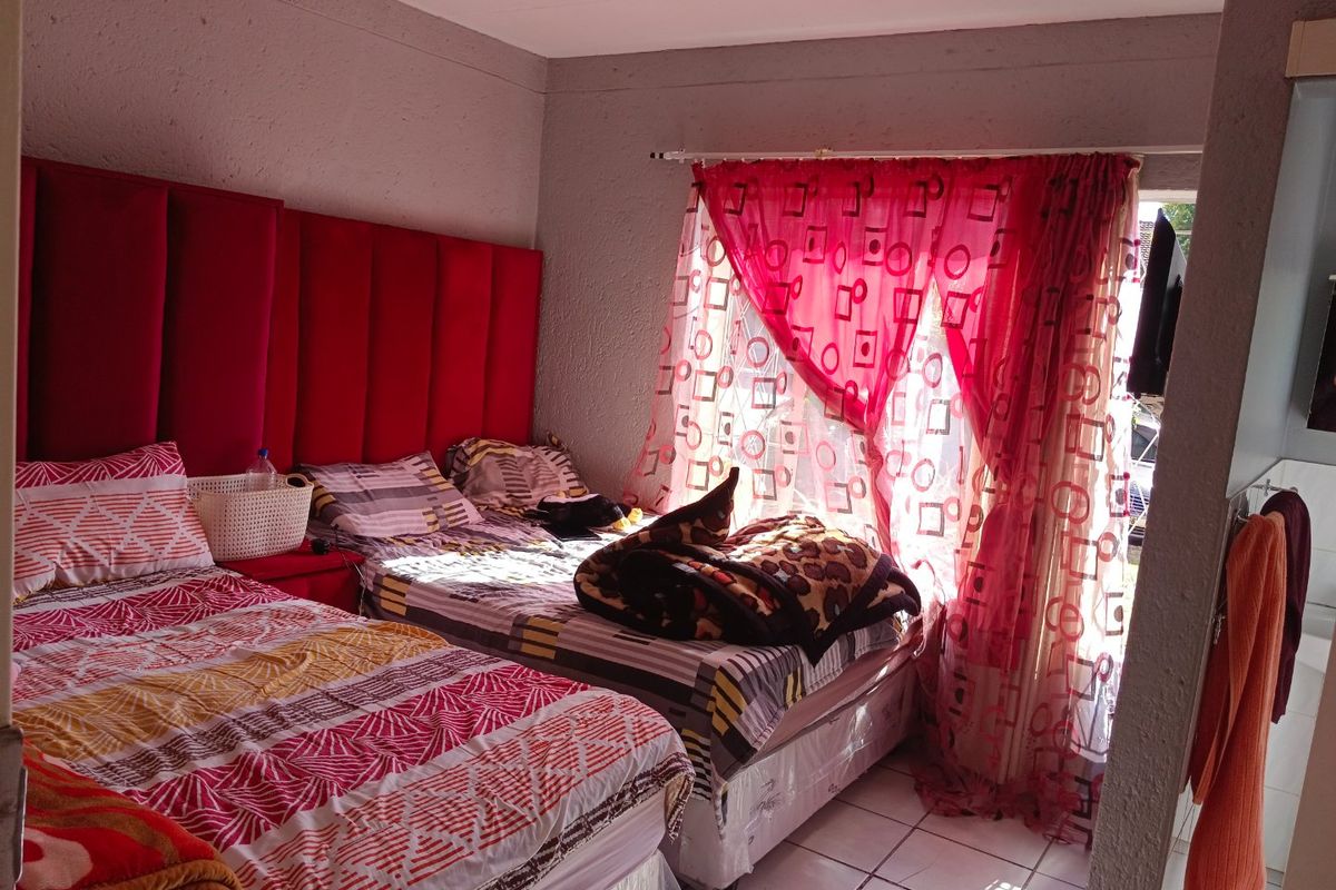A bedroom featuring tiled flooring and a large window with curtain rod, providing natural light to the space.